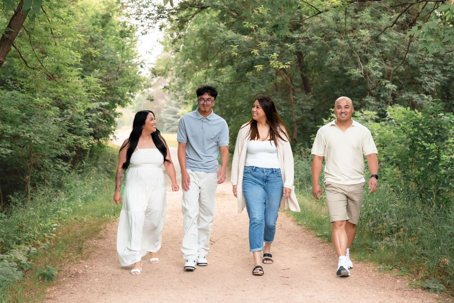 A group of friends walking together on a peaceful dirt trail surrounded by lush green trees and vegetation.