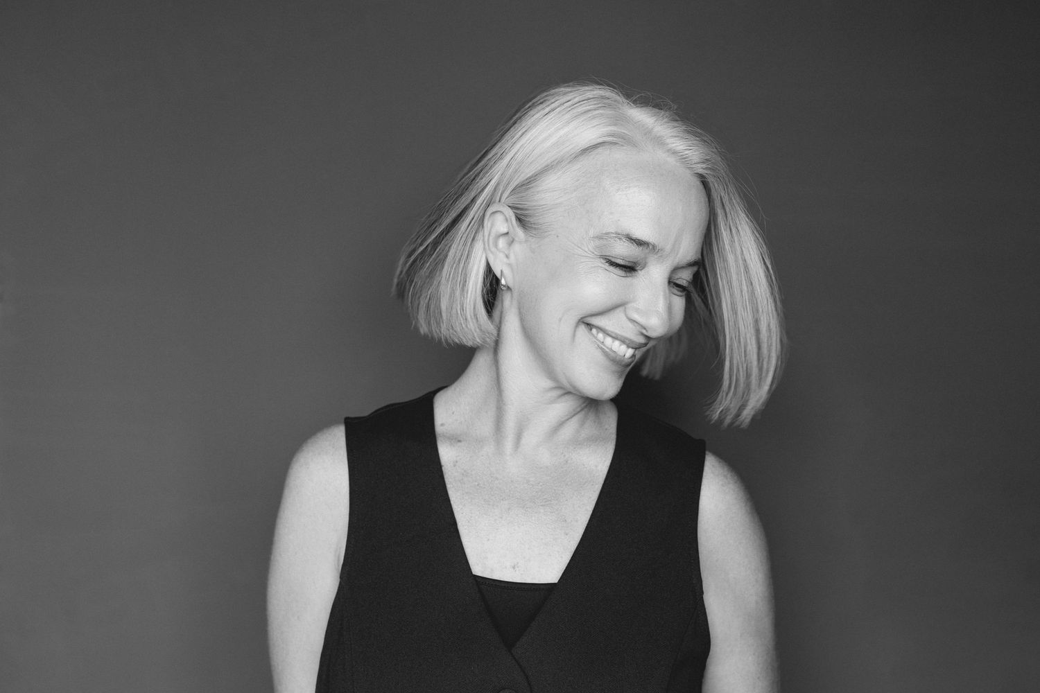 Black and white branding portrait of a smiling woman with short grey hair, natural and timeless.