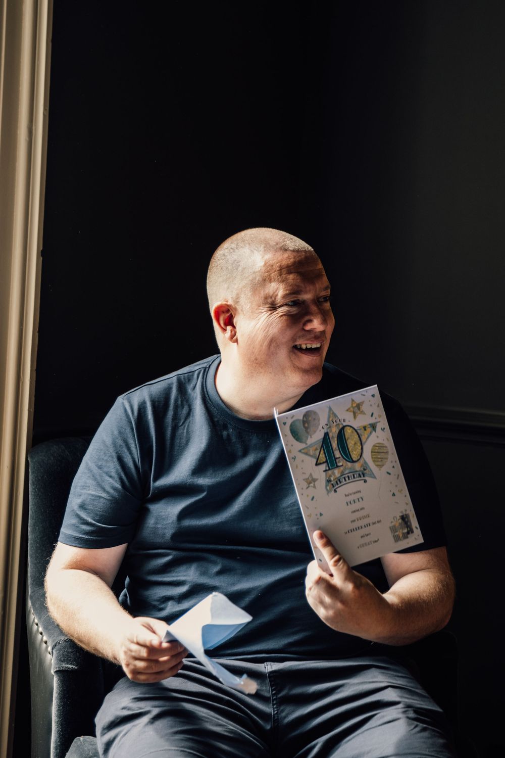 Person in blue shirt looking at greeting cards while sitting in dark room.
