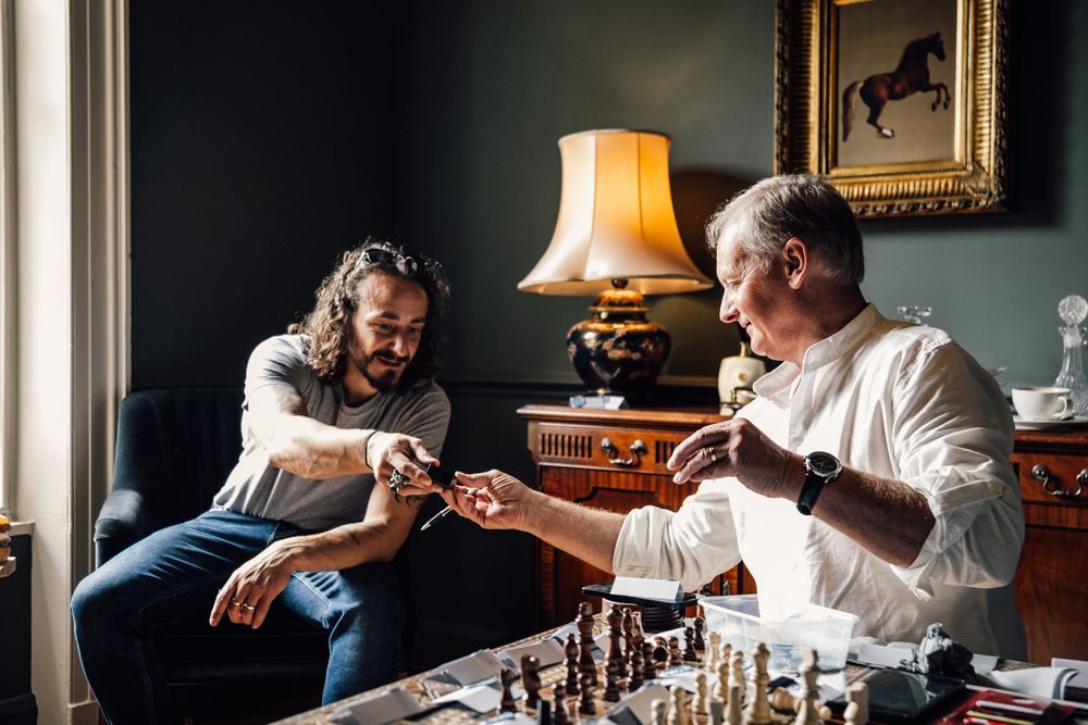People playing chess in an elegantly furnished room with warm lighting.