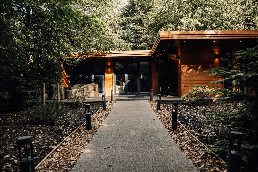 Wooden walkway leading to a rustic cabin surrounded by trees.