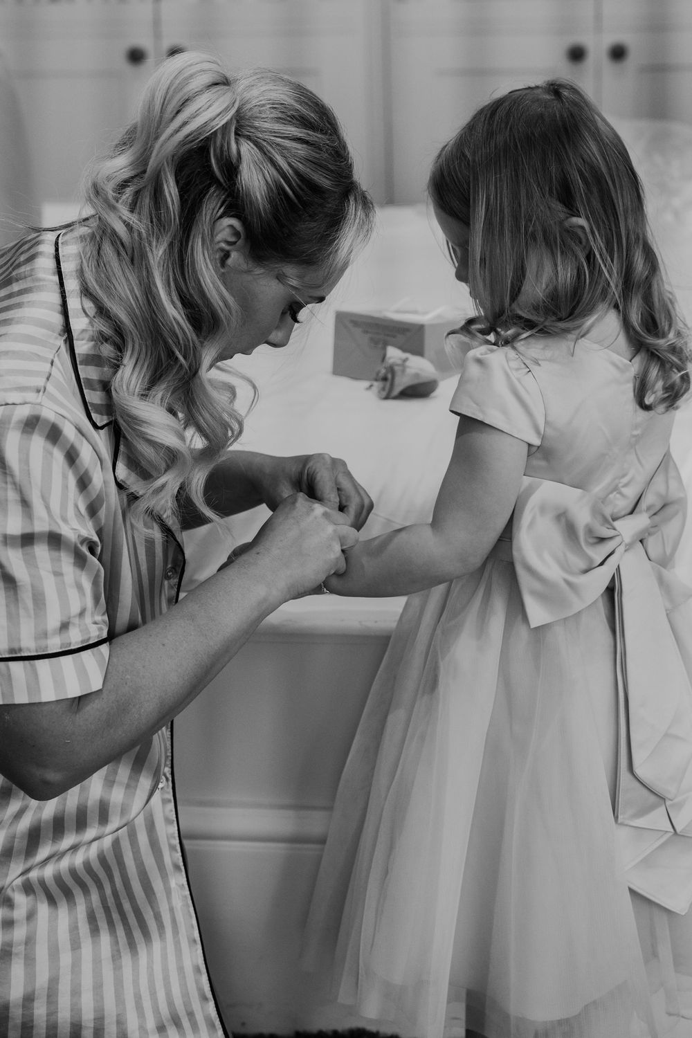 Black and white images of bridesmaids helping with wedding dress preparations.