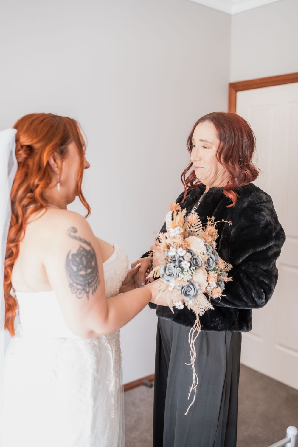 Two people share a moment during wedding preparations as they examine a dried flower bouquet.