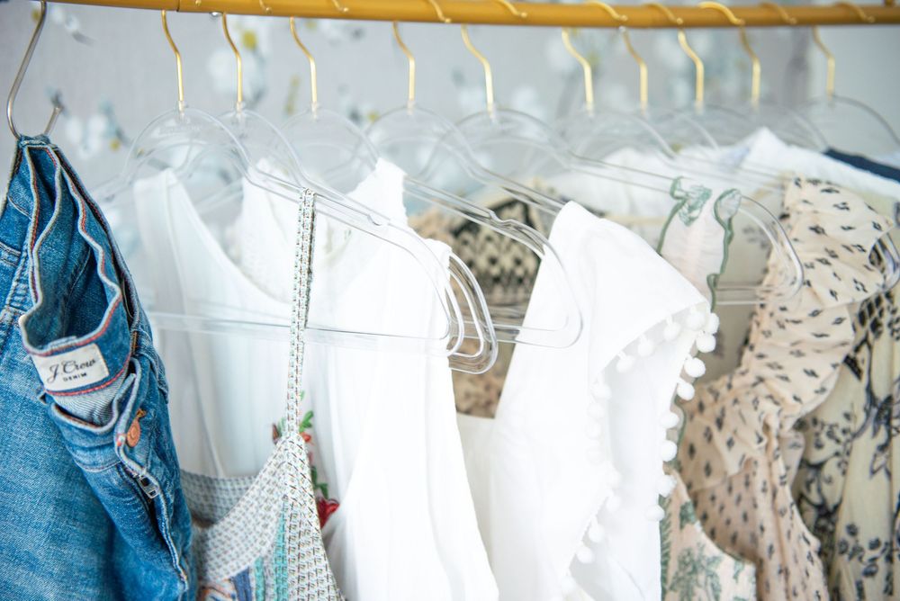 White and denim clothing hanging on hangers on a metal rack showing detailed fabric textures and patterns.