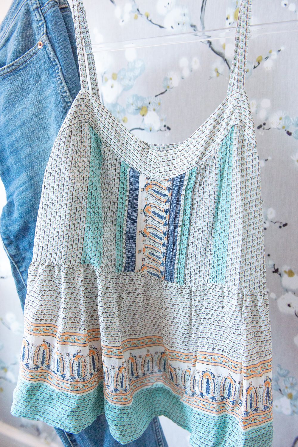 Turquoise and white crocheted baby dress with delicate lace pattern and peach embroidery details laid flat on light background.