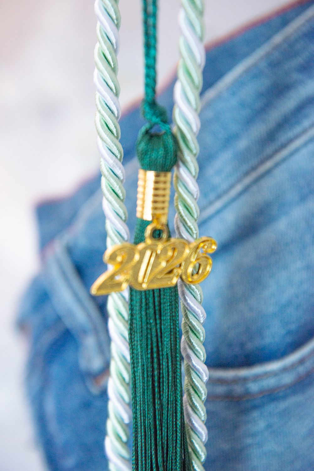 A series of five sequential close-up photos showing gold and green tassels against a blue denim background.