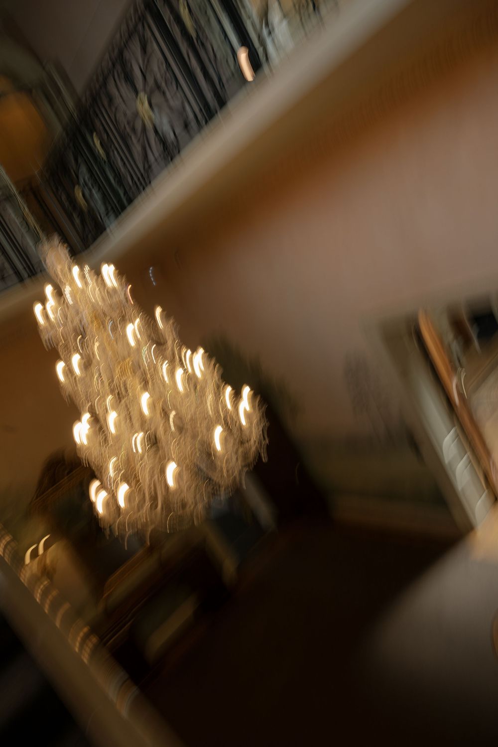 Elegant crystal chandelier glowing warmly in a dimly lit room.