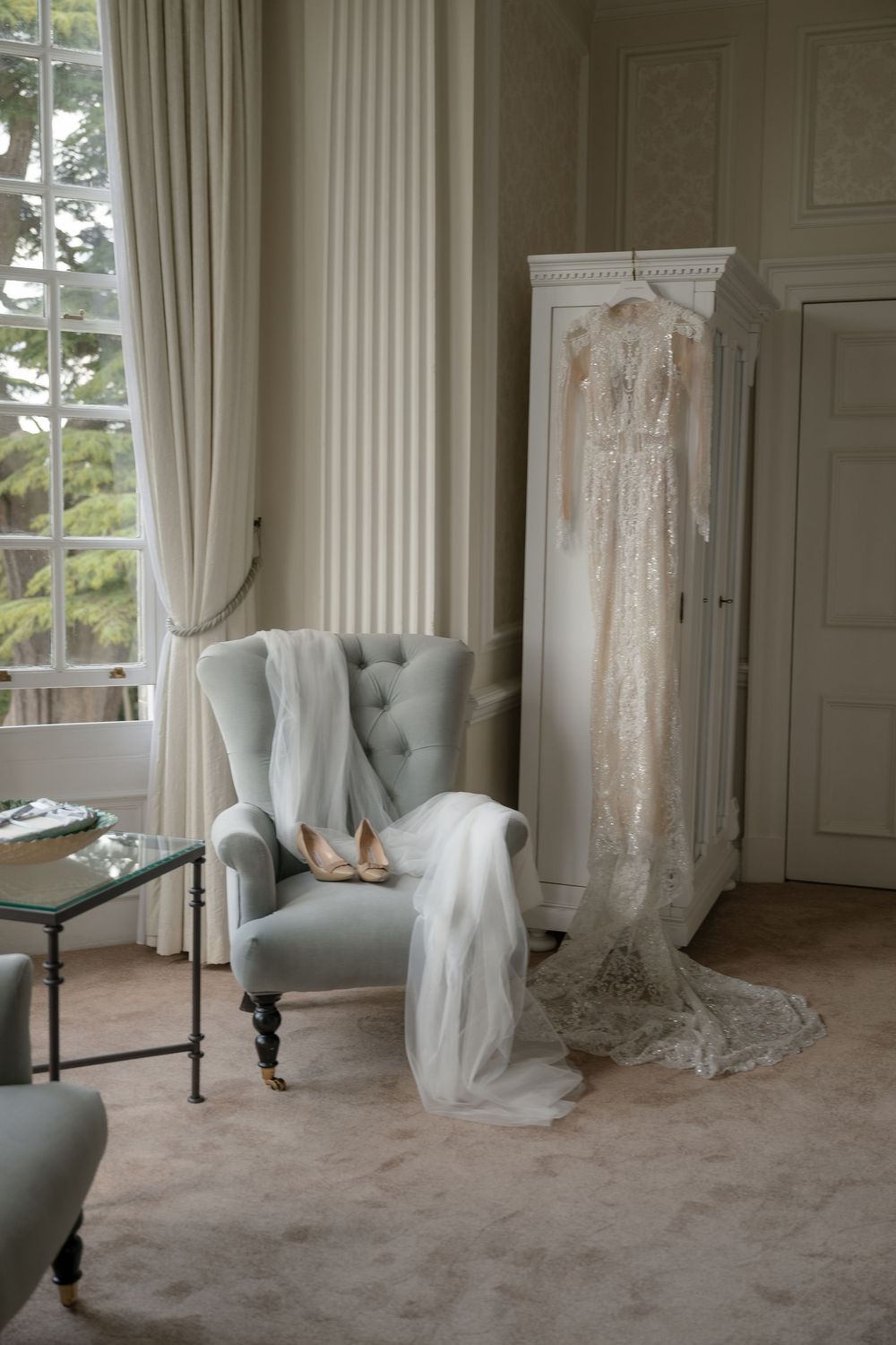 Wedding dress displayed in elegant room with white columns and natural light.
