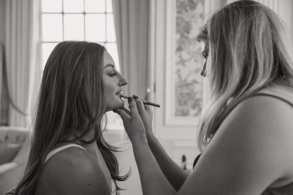 Black and white photograph capturing intimate wedding preparation moments.