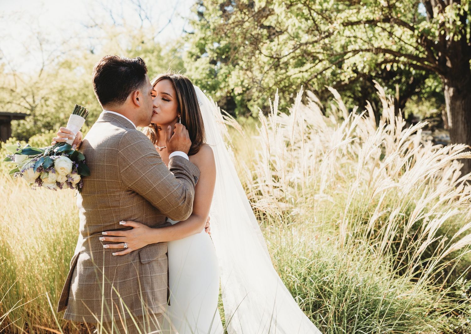 A tender wedding moment captured in a golden field with flowing pampas grass during a sun-drenched autumn day.