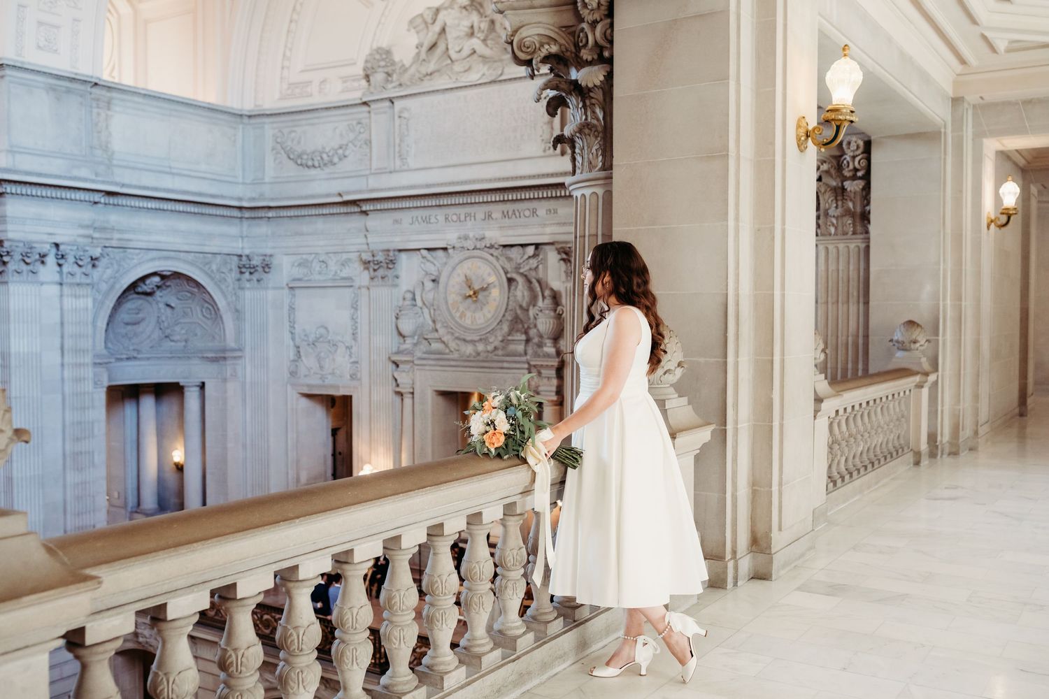 A white wedding dress flowing elegantly against ornate baroque architecture with classical details and marble railings.
