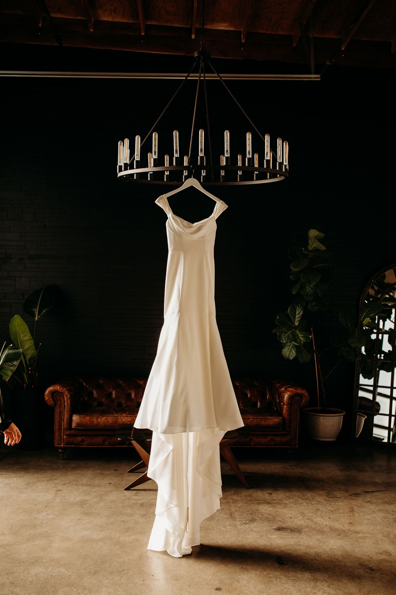 Artistic collection of white wedding dresses hanging in similar poses against dark backgrounds.
