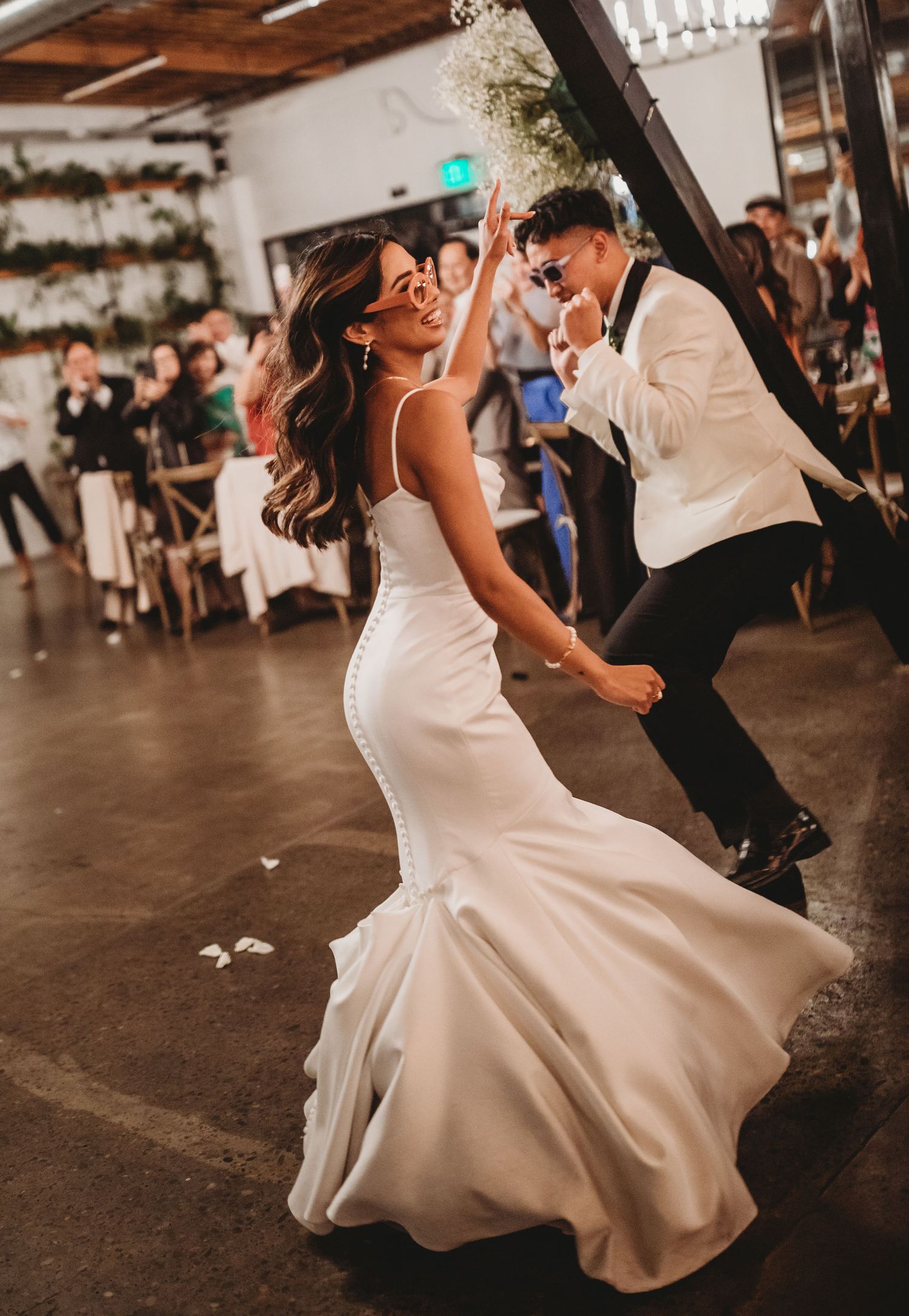 A couple dances on a rustic wooden floor during their first dance at a wedding reception.