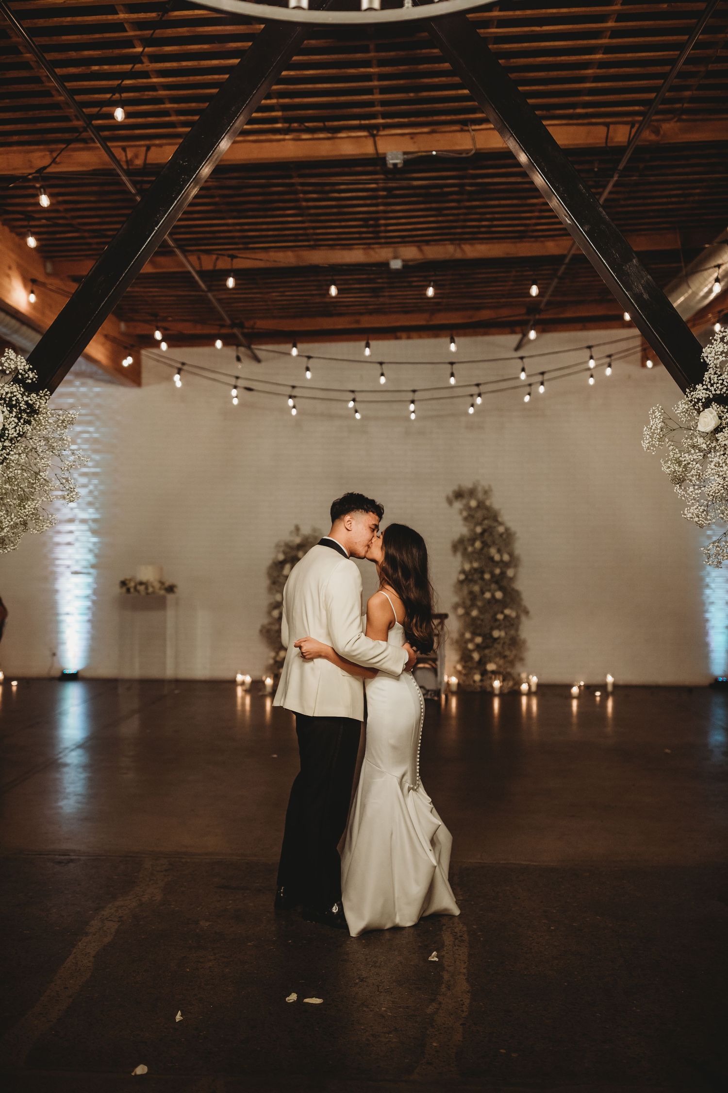 A romantic first dance in an elegant venue with string lights overhead and floral decor creating a dreamy atmosphere.