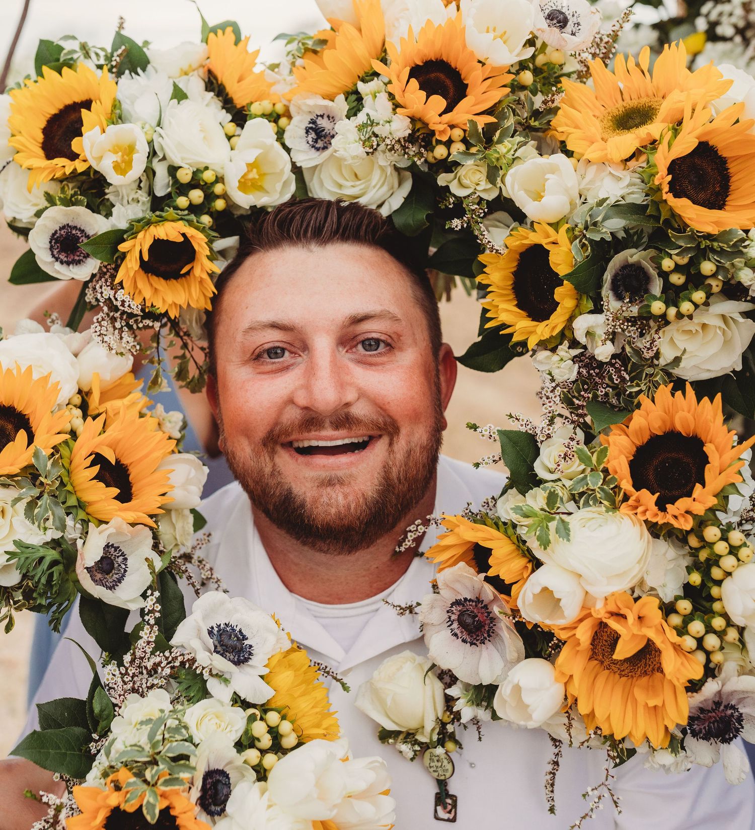 Vibrant sunflowers and white anemone floral arrangement with greenery creates a cheerful summer display.