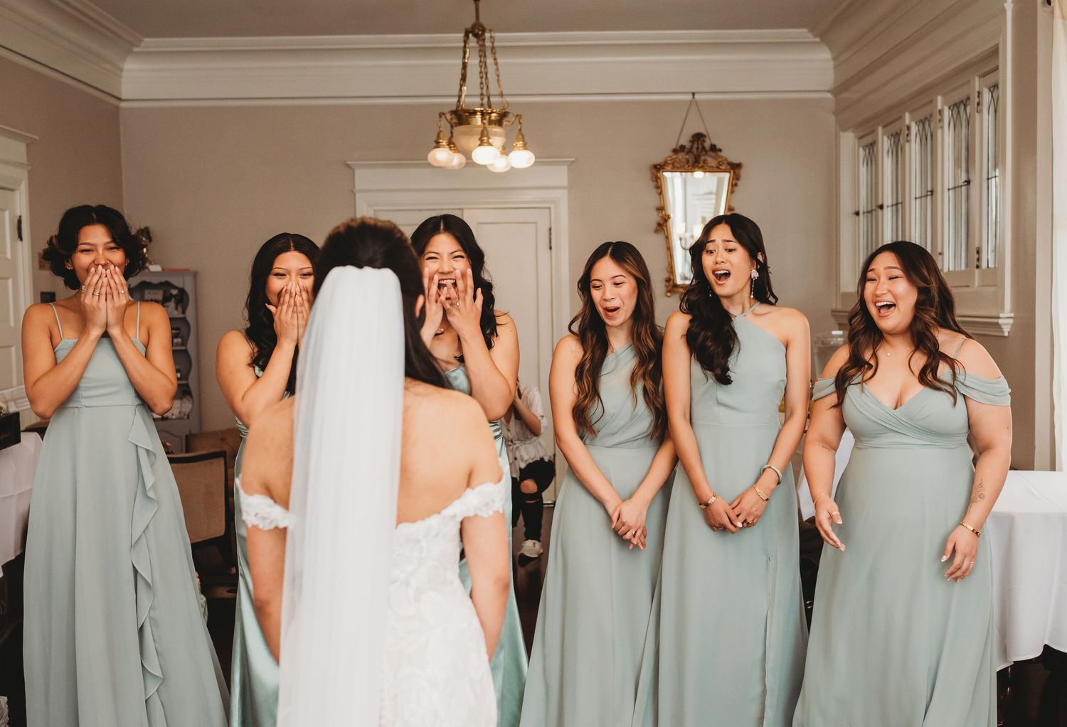Bridesmaids in matching mint green dresses pose together in an elegant indoor setting.