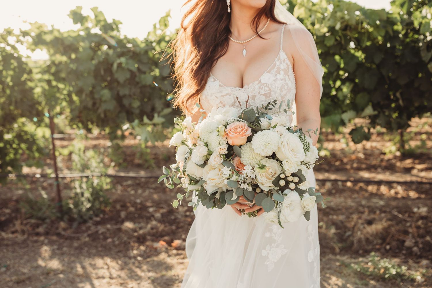 A beautiful white floral bridal bouquet with blush roses and eucalyptus greenery photographed outdoors in natural light.