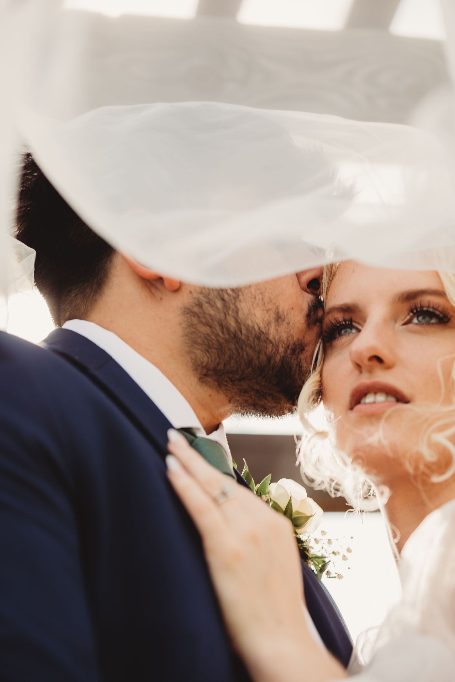 A romantic wedding couple under a veil share intimate moments in a series of closeup shots.