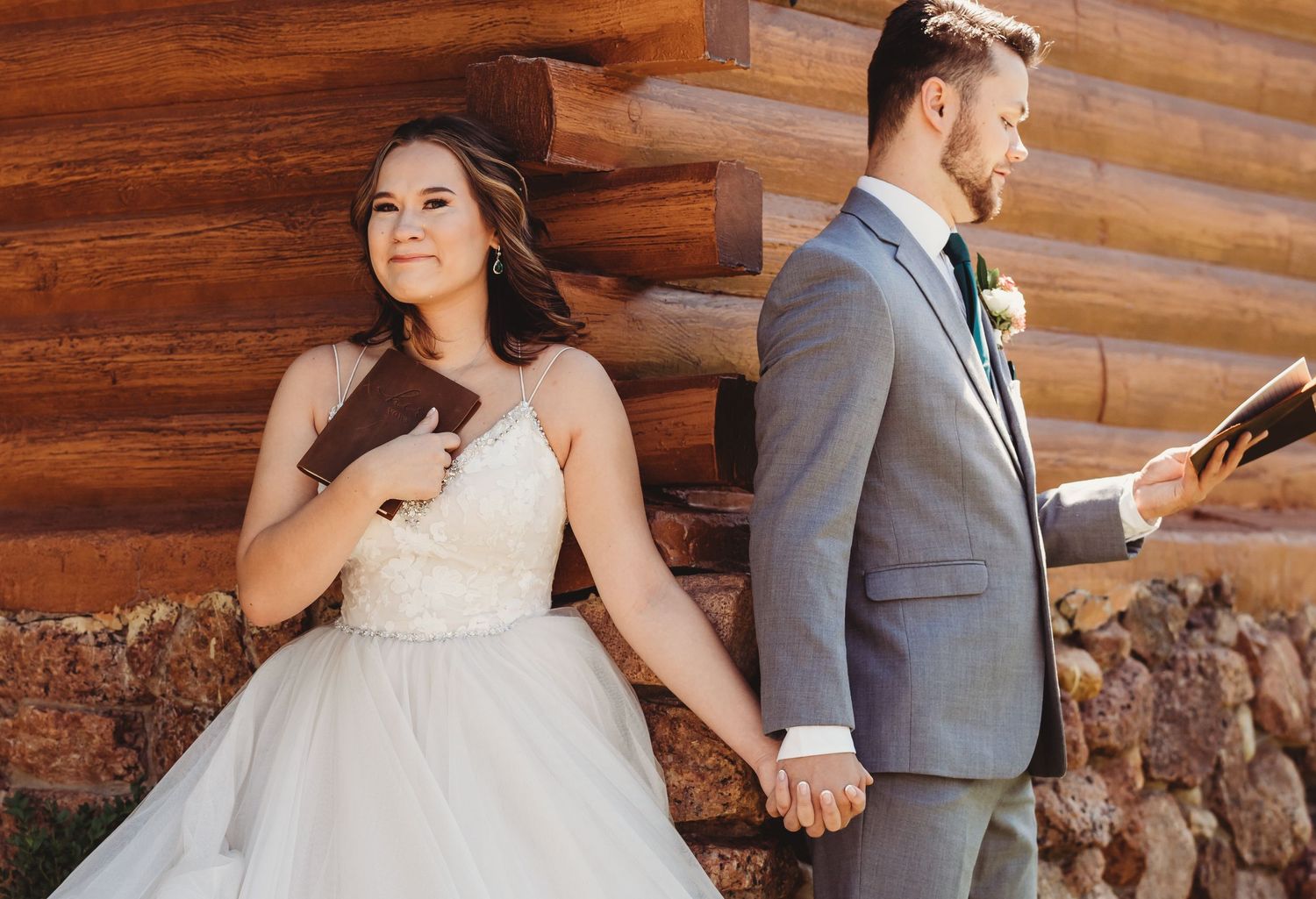 Wedding couple shares romantic moments against rustic wooden log cabin wall on their special day.