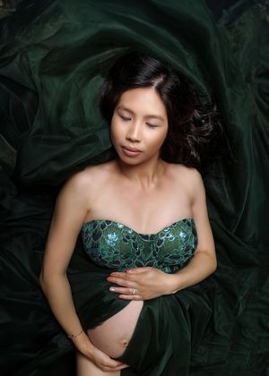 Artistic portrait against emerald green fabric with a strapless embellished dress in matching dark green tones.