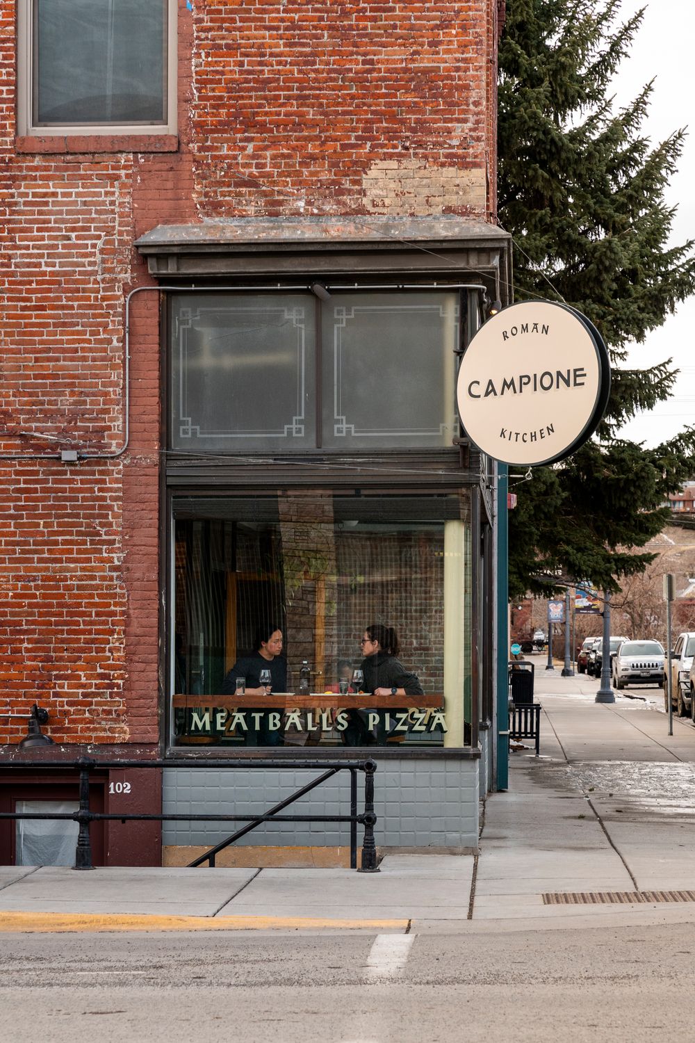 Exterior view of Campione restaurant with brick facade and meatballs pizza signage.