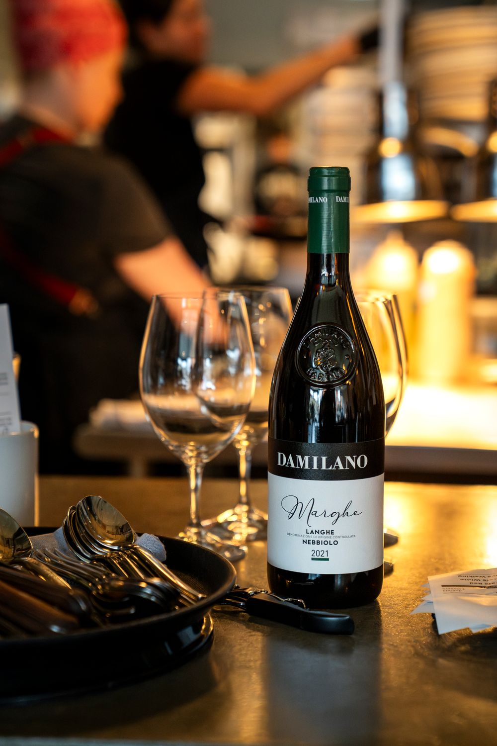 Damilano wine bottle and wine glasses on a restaurant table in warm lighting.