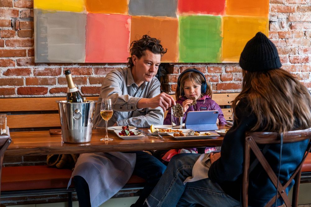Family dining together at a colorful restaurant with exposed brick walls.