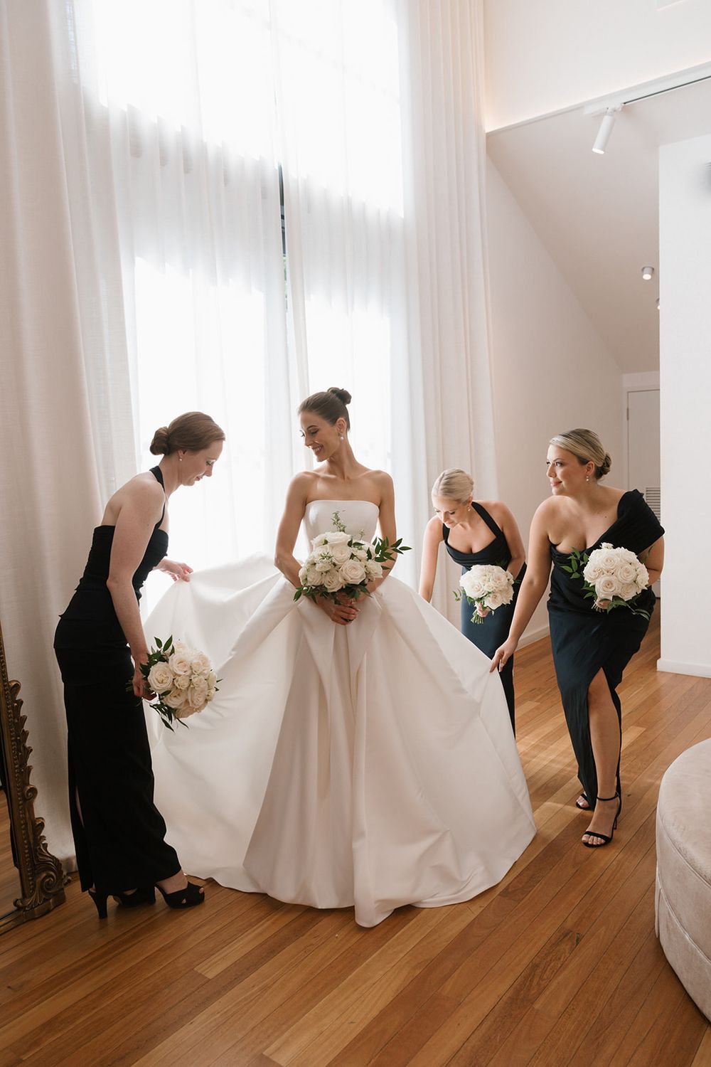Four sequential wedding preparation photos show a bride being helped with her white gown on a hardwood floor.