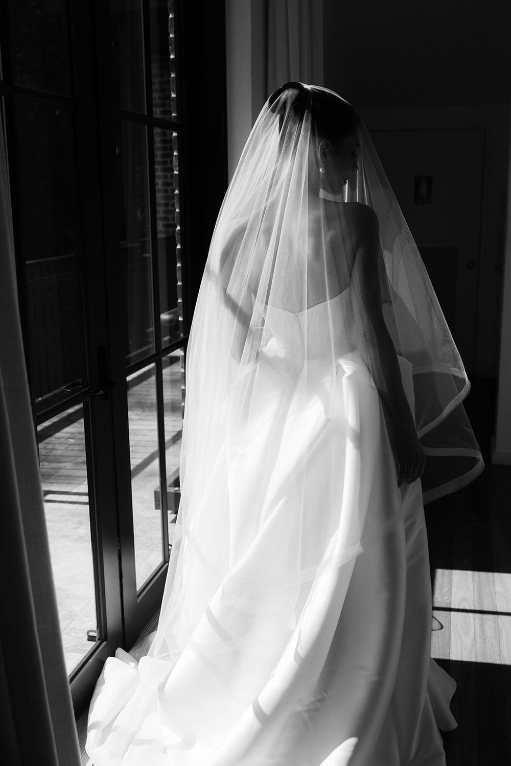 A black and white series showing a billowing white wedding dress photographed from behind against dark shadows.