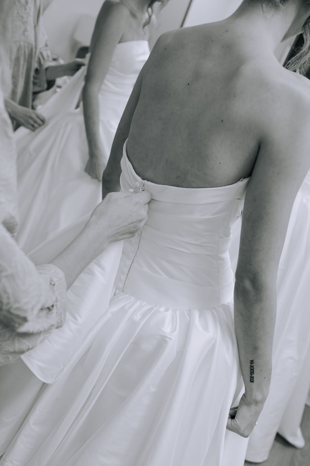 Close-up details of white wedding dresses shown in a series of black and white photographs.