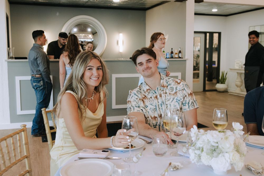 Wedding guests enjoying a casual reception gathering around tables in a modern indoor venue.
