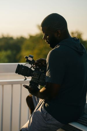 Silhouette of a videographer filming with professional camera equipment during golden hour.