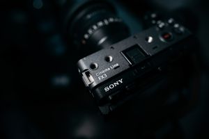 Close-up view of a black Sony digital camera body with controls visible in dramatic low-key lighting.