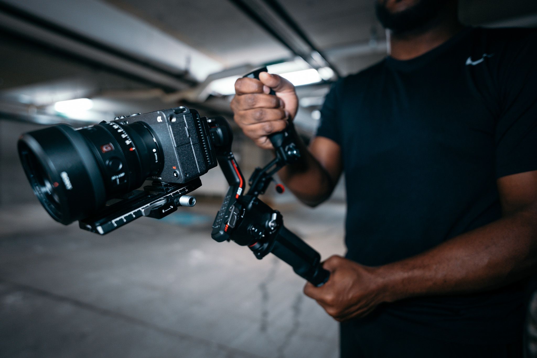 Close-up shot of hands holding professional camera equipment with stabilizer gimbal in dim lighting.
