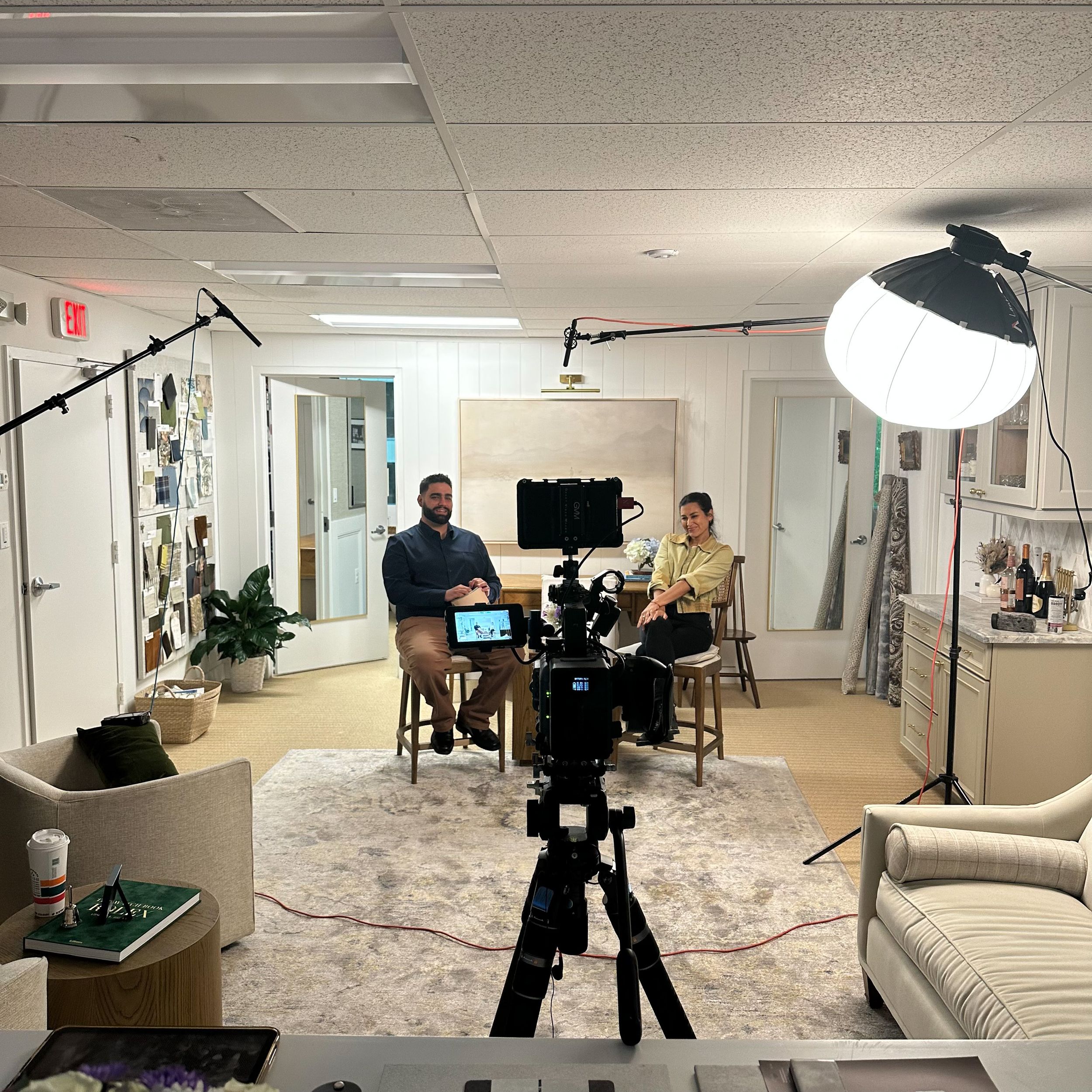 Professional photography studio setup with lighting equipment, furniture, and various camera angles in a modern office space.