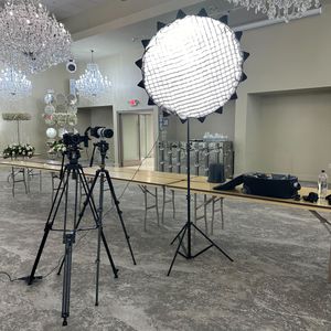 Professional studio setup with lighting equipment, tripods, and crystal chandeliers in a spacious indoor location.