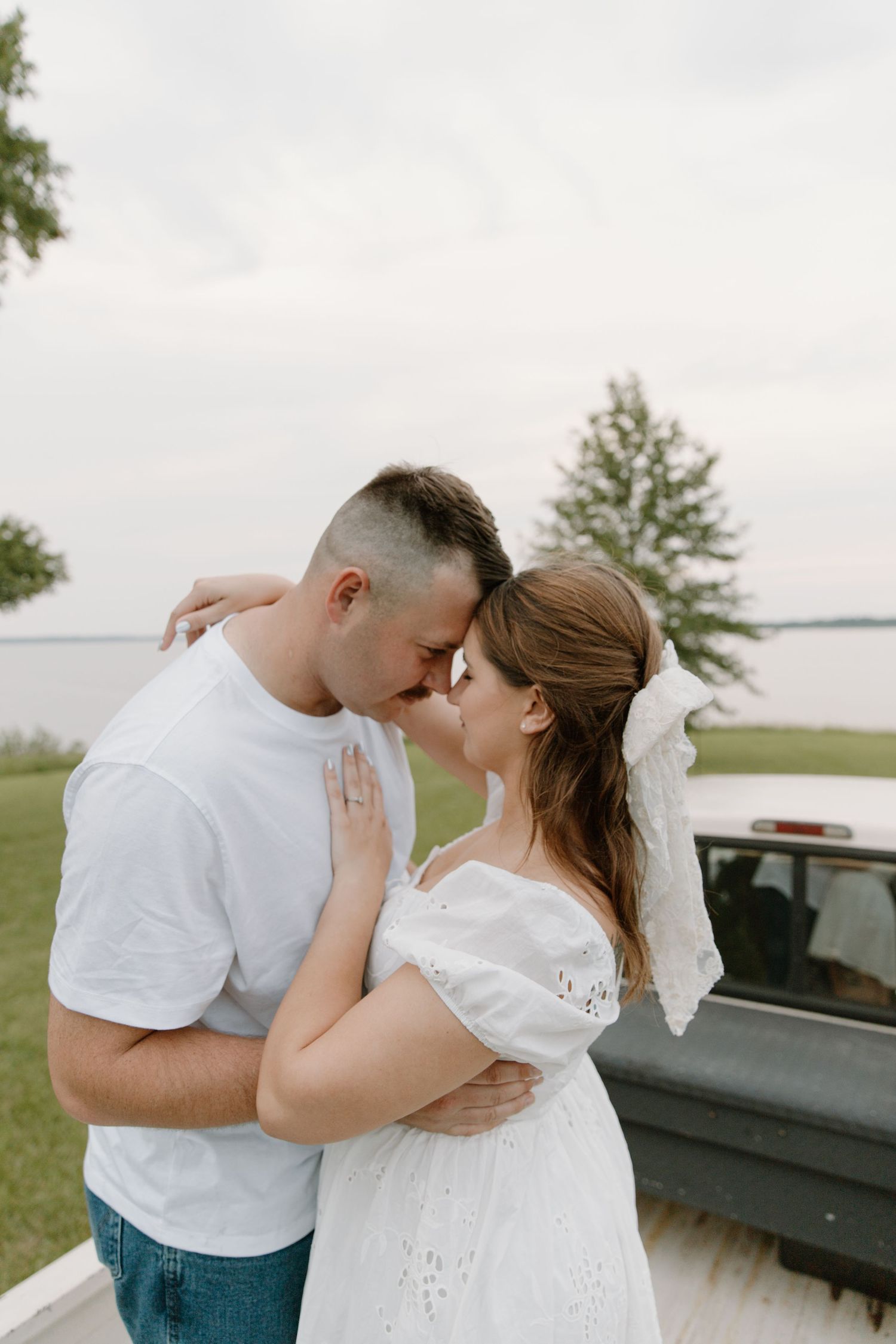 A couple lies together on a floral blanket in a field of dried grass during a romantic outdoor photoshoot.