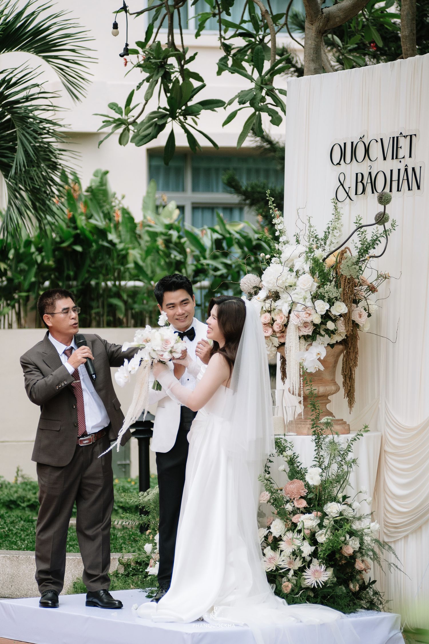 Officiant presents dove to newlyweds Quoc Viet and Bao Han at their elegant outdoor wedding ceremony.