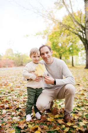 Precious autumn moment on fallen leaves as two people share a yellow maple leaf in a park.