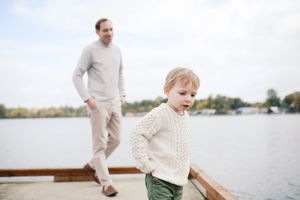 Family explores the beach together while walking along the water's edge on a bright sunny day.