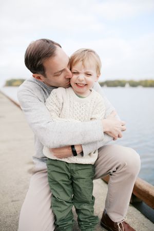 A tender moment of affection and connection is shared between parent and child by the waterfront.