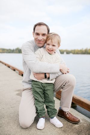 A tender moment shared beside a calm lake with a wooden bench in view.