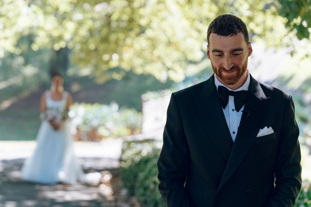 Groom in classic tuxedo smiling during first look wedding moment.