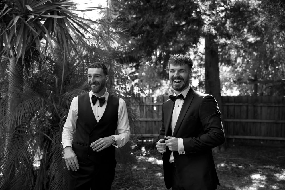 Two people in formal attire sharing drinks in a backyard garden setting.