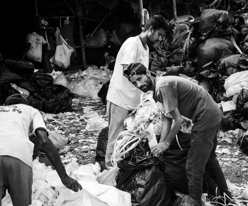 Workers sorting through piles of plastic waste in a recycling facility.