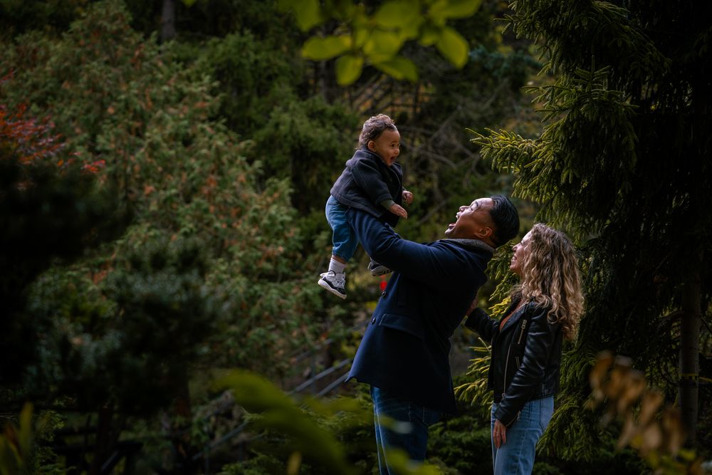 A couple embraces while dancing together in a lush green outdoor garden setting at sunset.