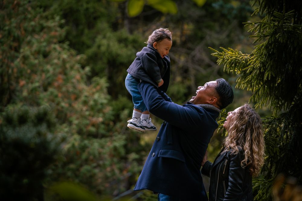 A couple shares joyful moments together in a lush green outdoor setting during a photoshoot.