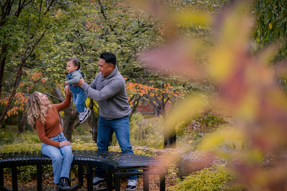 Couple enjoying an intimate moment together on a park bench surrounded by autumn foliage.