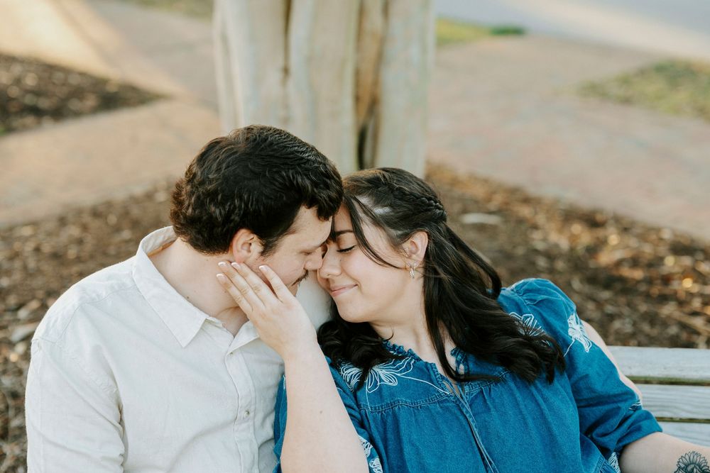 A tender moment shared between a couple sitting together, with one wearing white and the other in denim blue.
