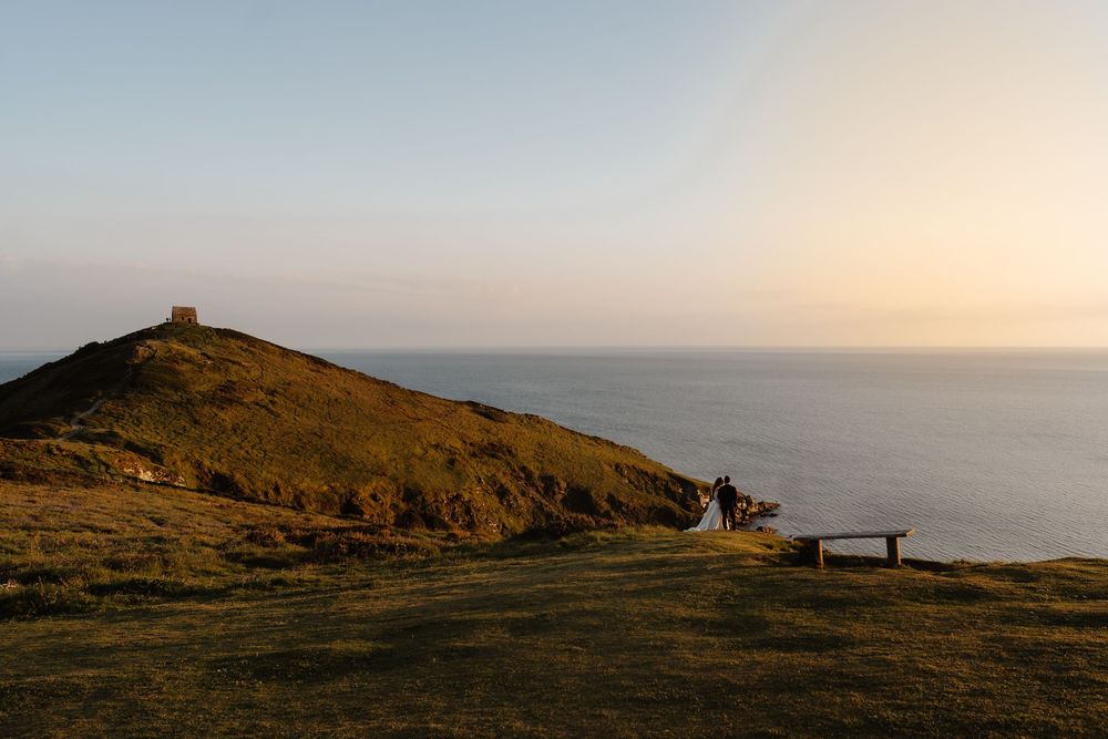 Sunset casts golden light over coastal cliffs and ocean vista.